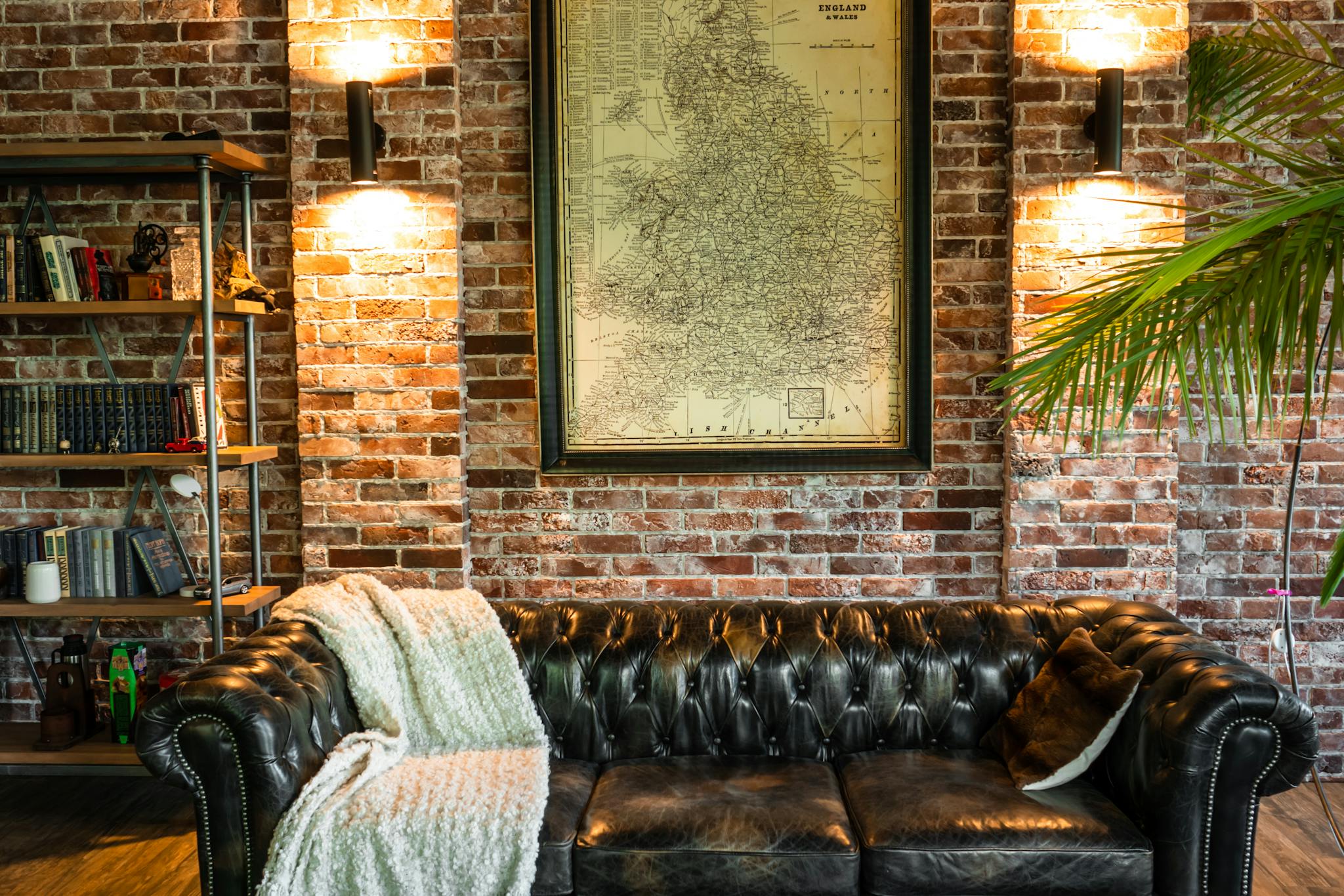 Warm and inviting living room with a vintage leather sofa against a brick wall and map decor.